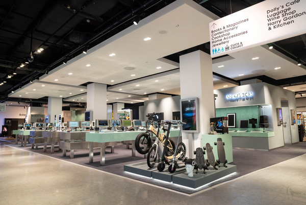 SMARTECH retail area with e-bikes. Sign: Books, Cookshop, Dolly's Cafe, Luggage, Wine Shop, Harry Gordon & Kitchen, Click & Collect.