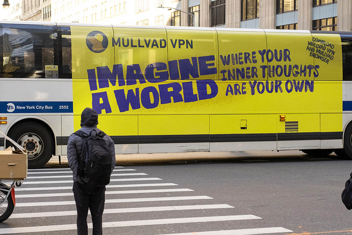 A person looks at a Mullvad VPN ad on an NYC bus: IMAGINE A WORLD WHERE YOUR INNER THOUGHTS ARE YOUR OWN. DOWNLOAD MULLVAD VPN AND MULLVAD BROWSER.