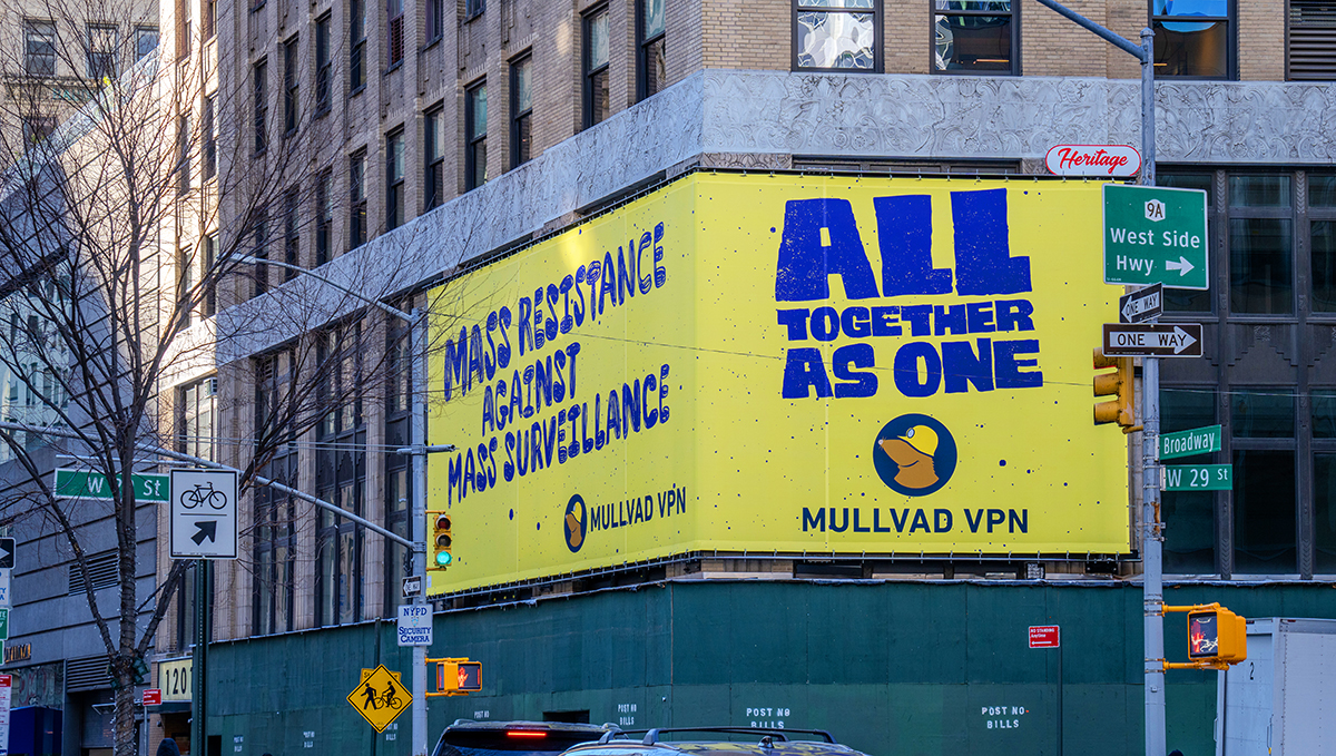 Yellow Mullvad VPN billboard on a city corner reading MASS RESISTANCE AGAINST MASS SURVEILLANCE and ALL TOGETHER AS ONE.